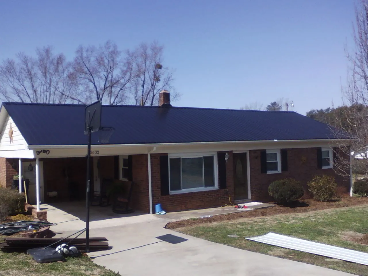 Finished dark blue metal roof on a brick ranch with a carport in Elk Mountain