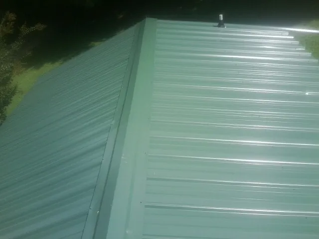 New green metal panels meeting at the ridge of a roof — Flat Roof Repair work by our crew in Elk Mountain
