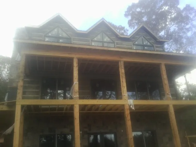 Dormers and porch framing on a large log home under construction — Roof Coating work by our crew in Elk Mountain