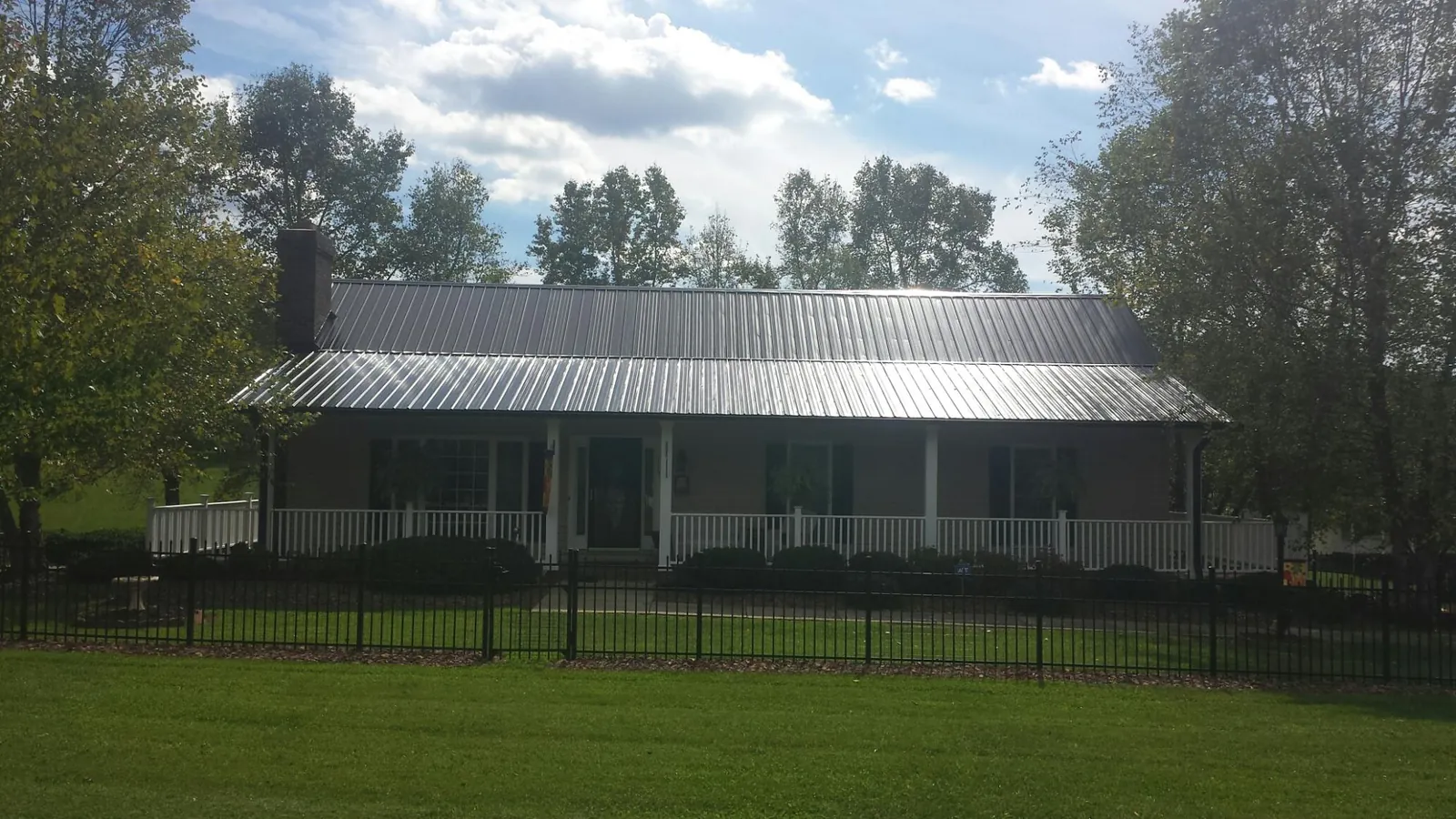 Gray metal roof on a brick ranch with a full width front porch — Gutter Guard Installation work by our crew in Elk Mountain