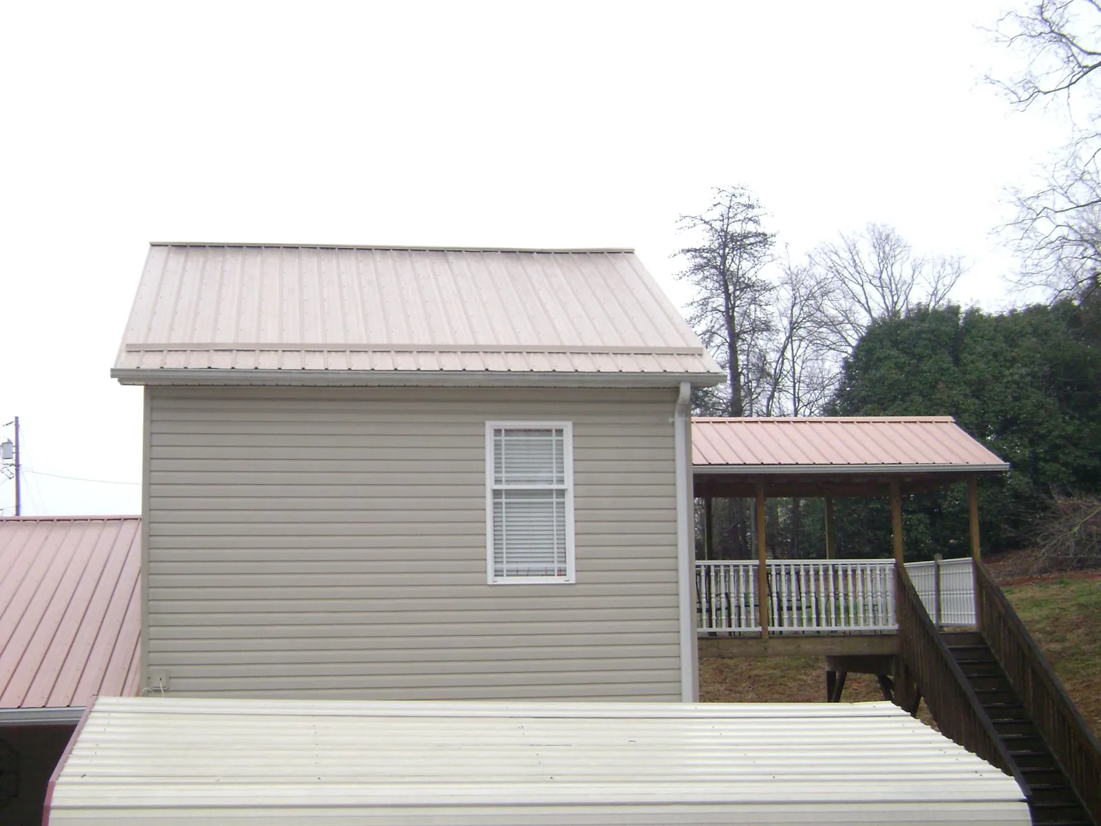 Tan metal roofs on a two story addition and attached porch, from a Roof Replacement job in Elk Mountain