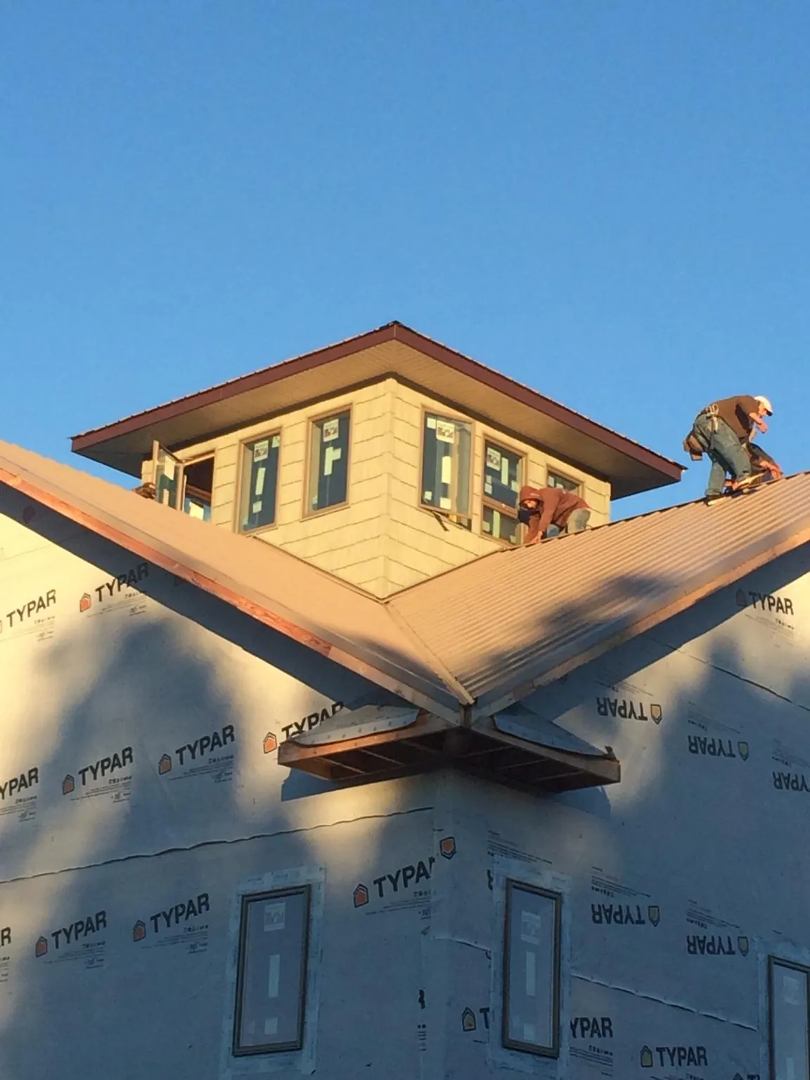 Roofers working around a rooftop cupola on a new metal roof at sunset — Roof Waterproofing in Elk Mountain by Roofing Brothers